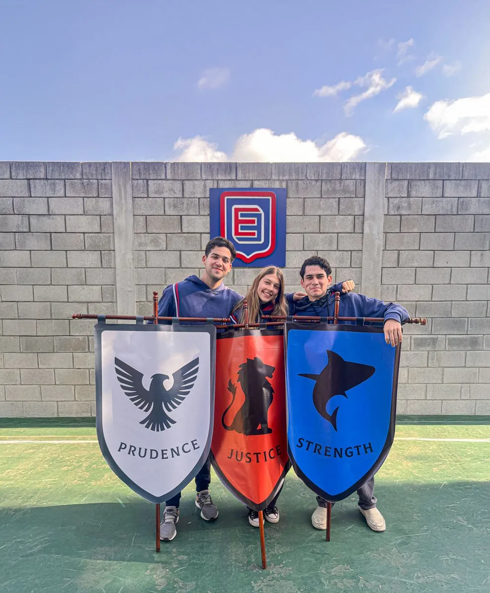 Tres estudiantes sostienen los estandartes de las houses: Prudence, Justice y Strength