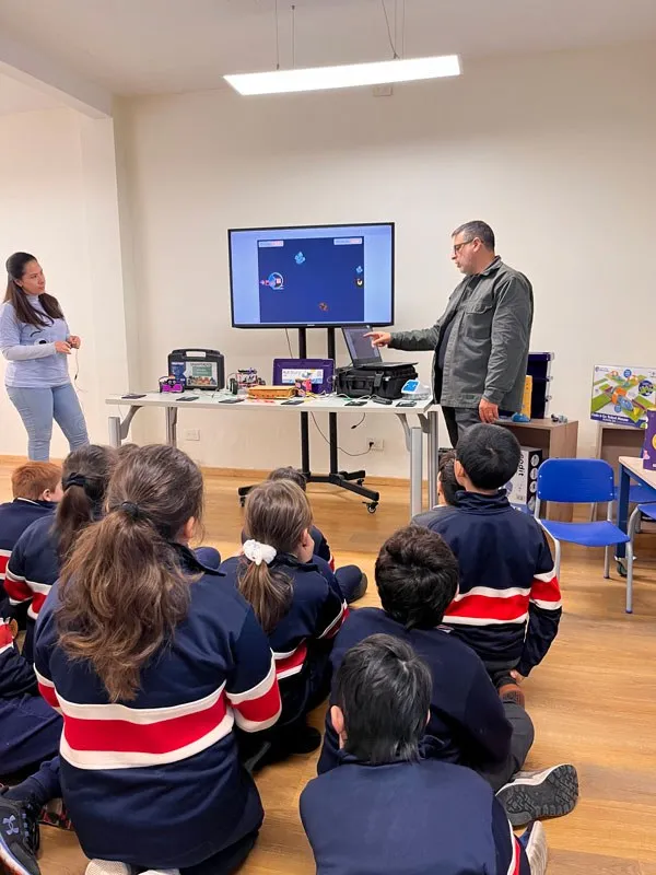 Clase de tecnología: un docente explica frente a la pantalla mientras los chicos siguen la actividad