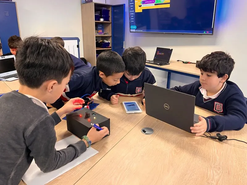Alumnos de Primary arman un circuito de robótica junto a una notebook